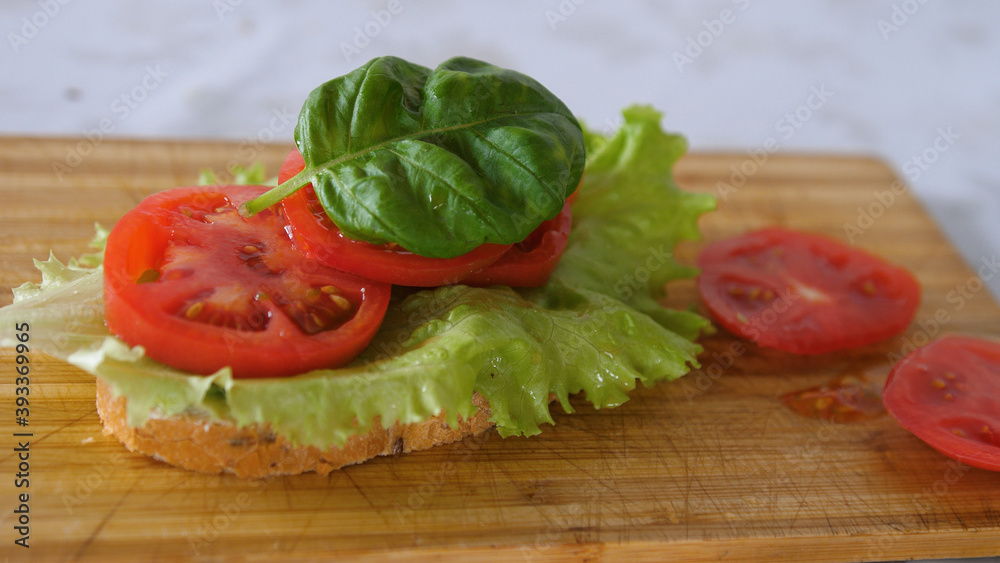 Finishing Homemade nutrition breakfast with sandwich, lettuce leaf, tomato Finishing Homemade nutrition breakfast with sandwich, lettuce leaf, tomato