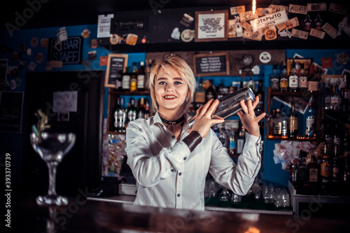 Experienced girl bartending demonstrates his skills over the counter while standing near the bar counter in bar photo