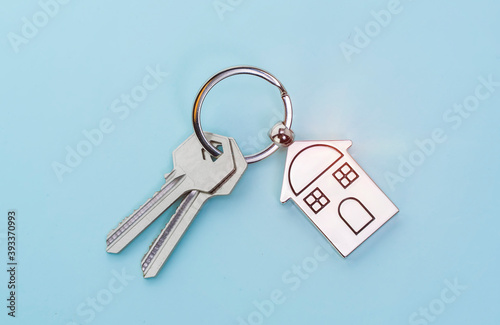 key chain with house symbol and keys on blue background,Real estate concept