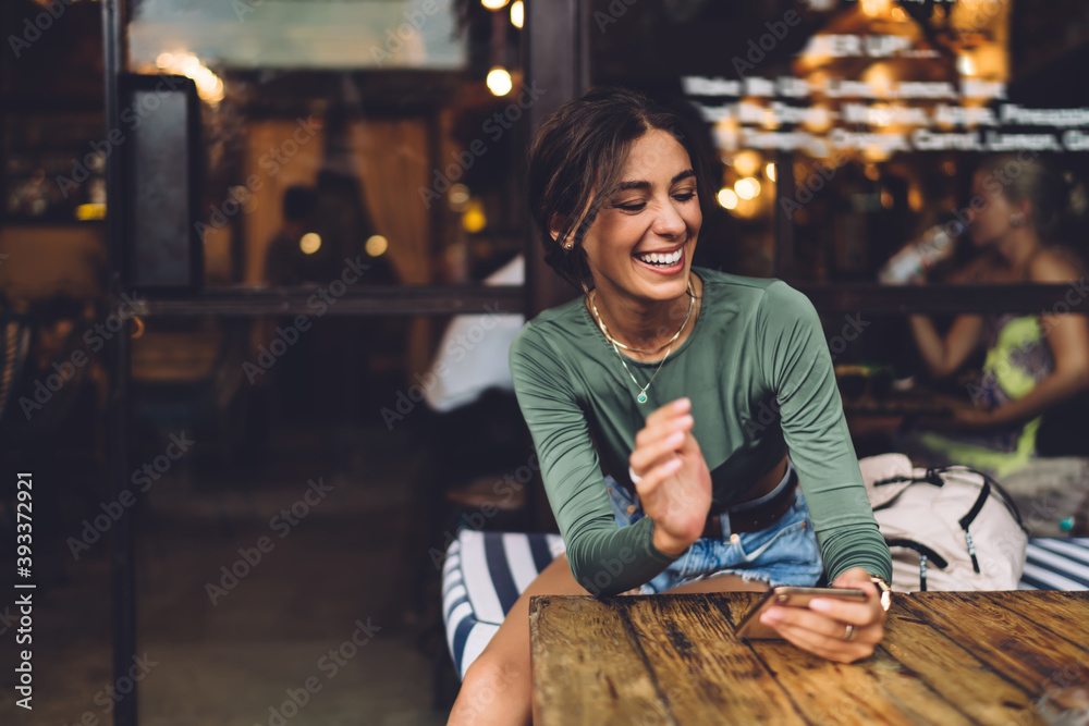 Joyful woman with smartphone in cafe