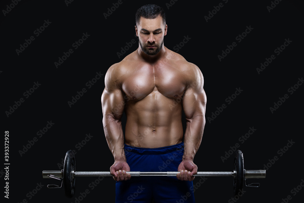 Handsome fitness man is standing with a heavy barbell ready to workout isolated on black background Handsome fitness man is standing with a heavy barbell ready to workout isolated on black background