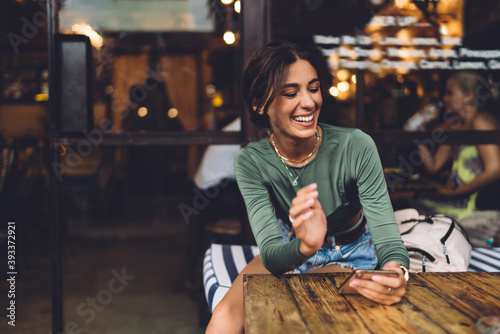 Joyful woman with smartphone in cafe