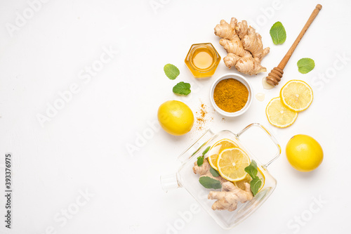 Hot tea with ginger and turmeric, honey and lemon in glass cup. Immune system support with alternative medicine.  White background, Top view, Сopy space