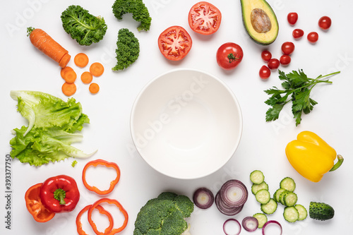 Creative layout made of variety of vegetables for making salads. Carrots, lettuce, kale, tomato, cucumber, broccoli, avocado, red bell pepper, onion. White background, top view, copy space