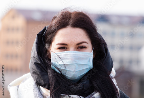Young woman in a protective face mask on a city street during quarantine