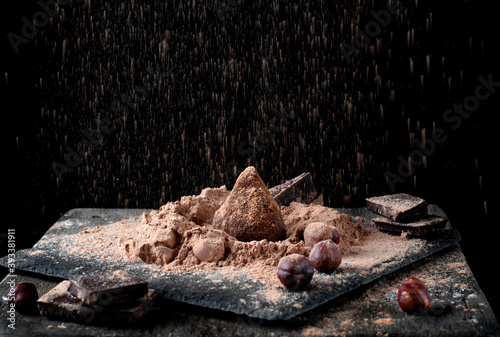 Chocolate truffle sprinkled with cacao and golden powder against the black background 