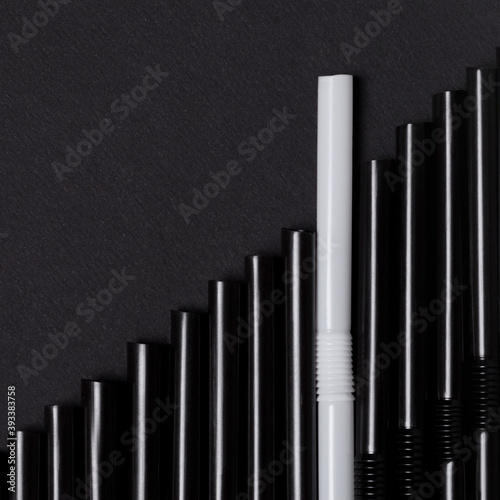 Group black cocktail straws straw on dark background. Individuality concept.