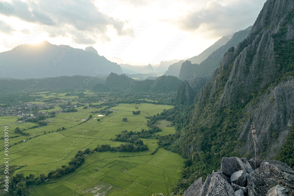 Naklejka premium Beautiful Sunset Views of Mountainous in Vang Vieng City which Popular for Tourists. View of Rice Fields Under the Mountains.
