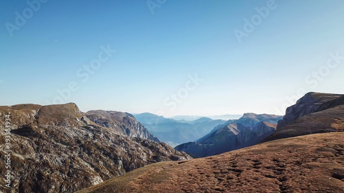 A panoramic view on the plain on top of a mountain in Hochschwab region in Austrian Alps. The flora overgrowing the slopes is turning golden. Autumn vibes. Many mountain chains in the back. Wilderness