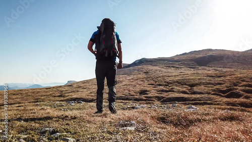 A panoramic capture of a man hiking in Hochschwab region in Austrian Alps. The flora overgrowing slopes is turning golden. Autumn vibes in the mountains. Idyllic landscape. Freedom and wilderness