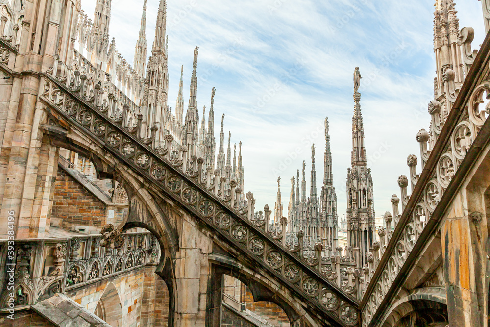 Roof of Milan Cathedral Duomo di Milano with Gothic spires and white marble statues. Top tourist attraction on piazza in Milan, Lombardia, Italy. Wide angle view of old Gothic architecture and art. Roof of Milan Cathedral Duomo di Milano with Gothic spires and white marble statues. Top tourist attraction on piazza in Milan, Lombardia, Italy. Wide angle view of old Gothic architecture and art.