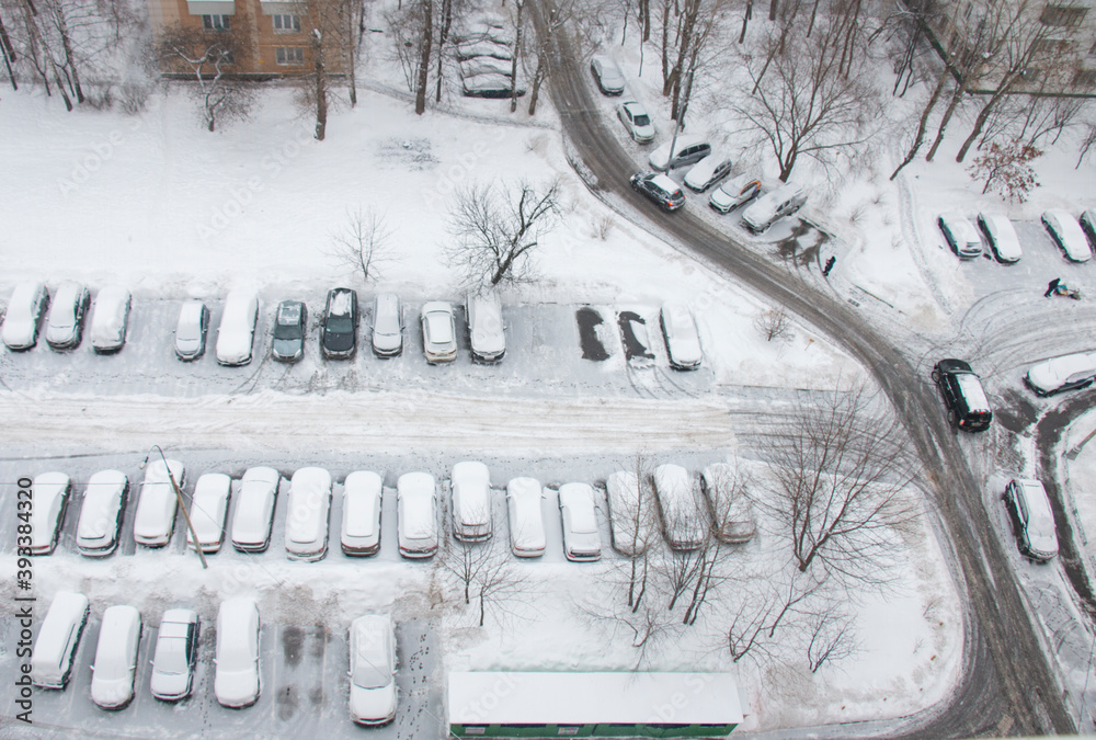 Snow-covered cars during snowfall in the city in the parking lot after ...