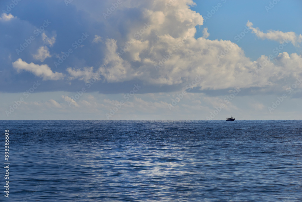 a fishing boat in the middle of the sea in the clouds on a beautiful autumn day
