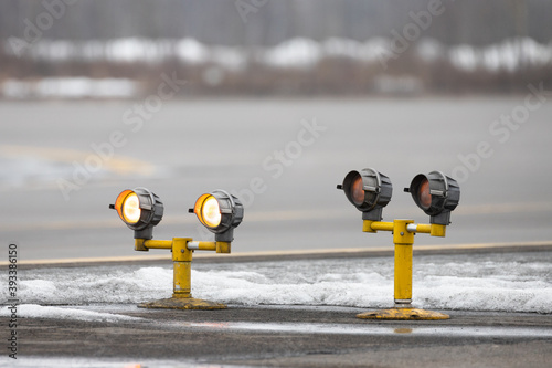 Fotografia Airport runway guarding lights, traffic safety lights in winter time