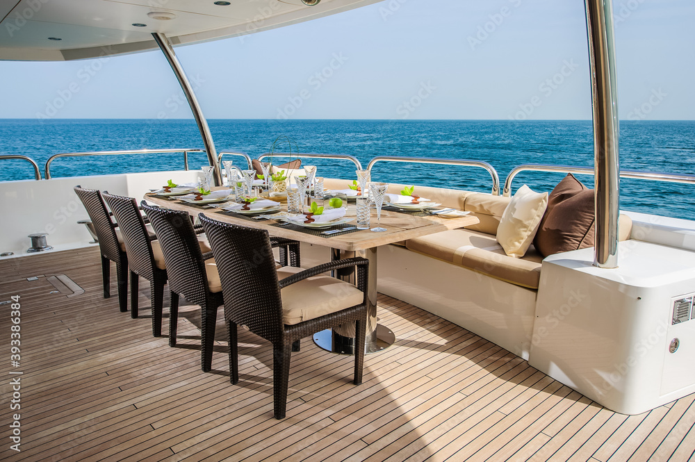 Summer day yacht deck with served table and open sea.