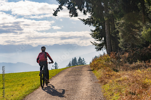 Woman as silhouette riding her electric mountain bike in the Allgaeu alps near Oberstaufen with awesome view into the Bregenz Wald Mountains, Vorarlberg , Austria