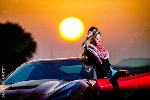 Young woman poses near car in desert in sunset