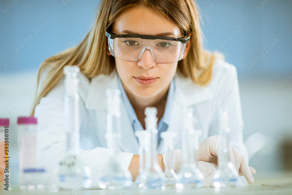 Female medical or scientific researcher looking at a flasks with solutions in a laboratory Female medical or scientific researcher looking at a flasks with solutions in a laboratory