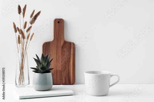 A mug and potted houseplant  a book  a transparent vase and a wooden board. Eco-friendly materials in interior decor  minimalism. Copy space  mock up.