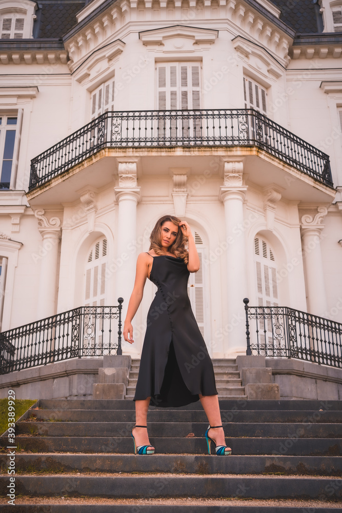 Lifestyle, blonde Caucasian in a glamorous dress and blue heels in a rustic house. The young pretty girl on the stairs of the white house Lifestyle, blonde Caucasian in a glamorous dress and blue heels in a rustic house. The young pretty girl on the stairs of the white house