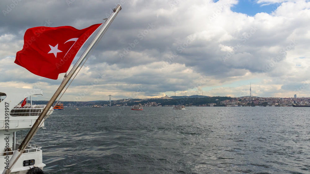 Fototapeta premium Turkish flag waving over the Bosphorus in Istanbul, Turkey