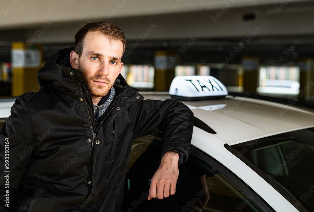 Young taxi driver posing with his car