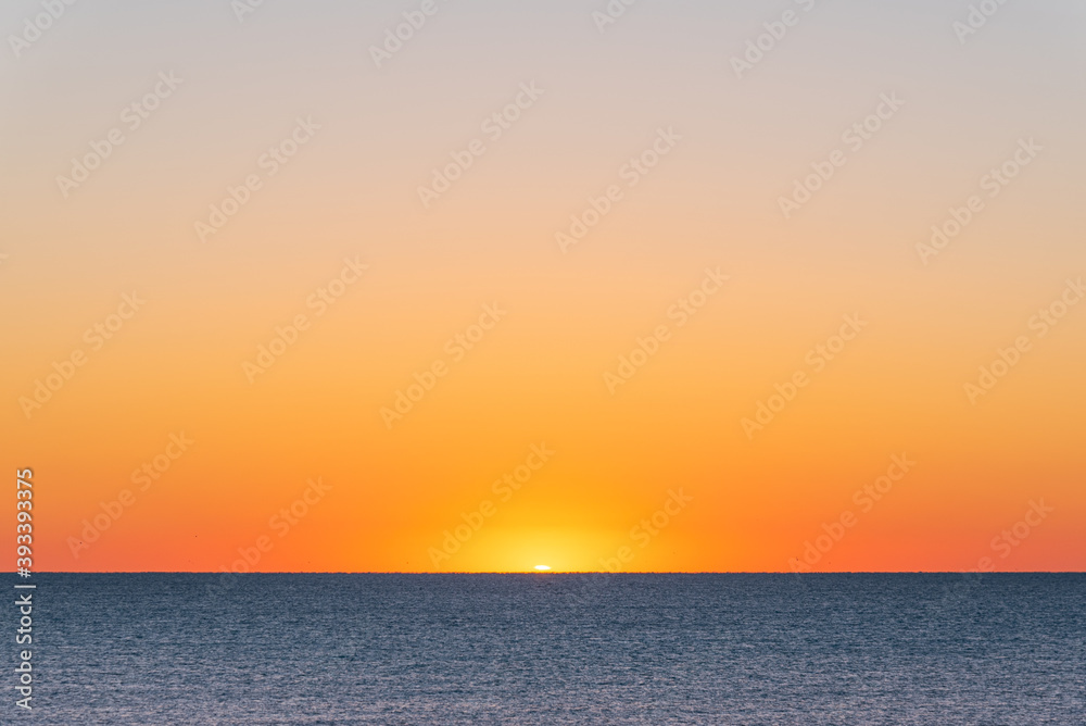 Orange sunrise over the ocean and sandy beach