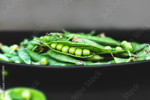 Peas on a black background. Peas in a plate. Summer fruits. Green and black