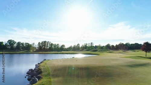 golf hole with sun over a lake