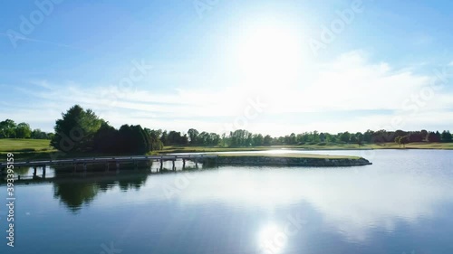 Island golf hole with sun flare over a lake