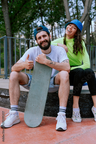 Couple having fun together with skateboard and showing thumb up
