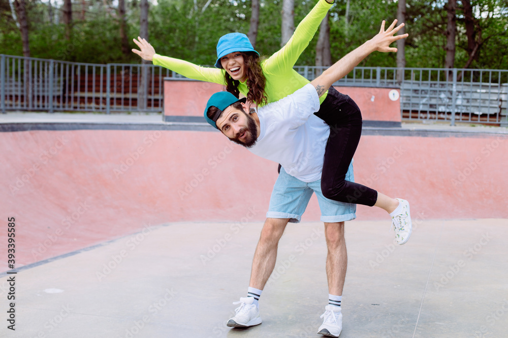Beautiful young couple enjoying outdoors in city skateboarding park