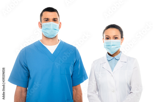 Nurse and african american doctor in medical masks looking at camera isolated on white
