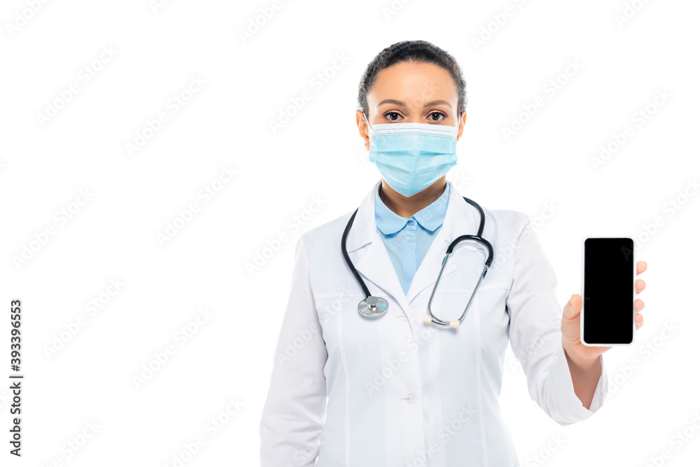 African american doctor in medical mask holding smartphone with blank screen isolated on white
