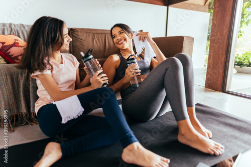 Latin mother and daughter rest after exercising at home.