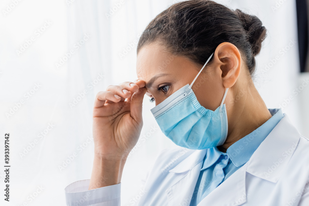Exhausted african american doctor in medical mask looking away in clinic Exhausted african american doctor in medical mask looking away in clinic