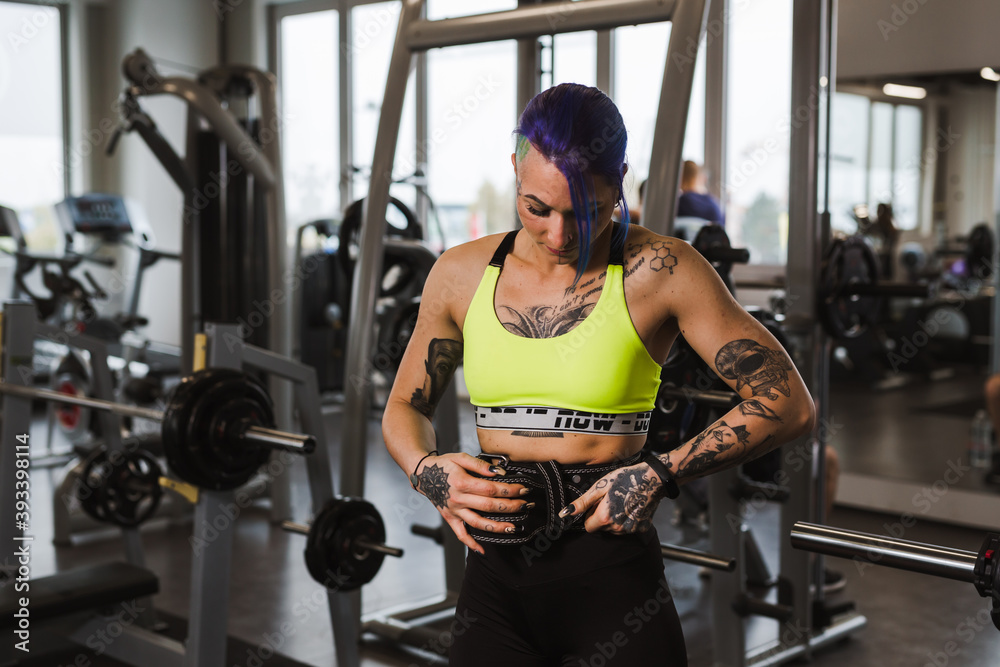 Fototapeta premium tattooed woman preparing for power lifting in gym