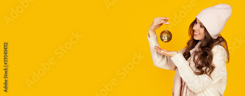 Happy young smiling woman holding a christmas tree ball promotin