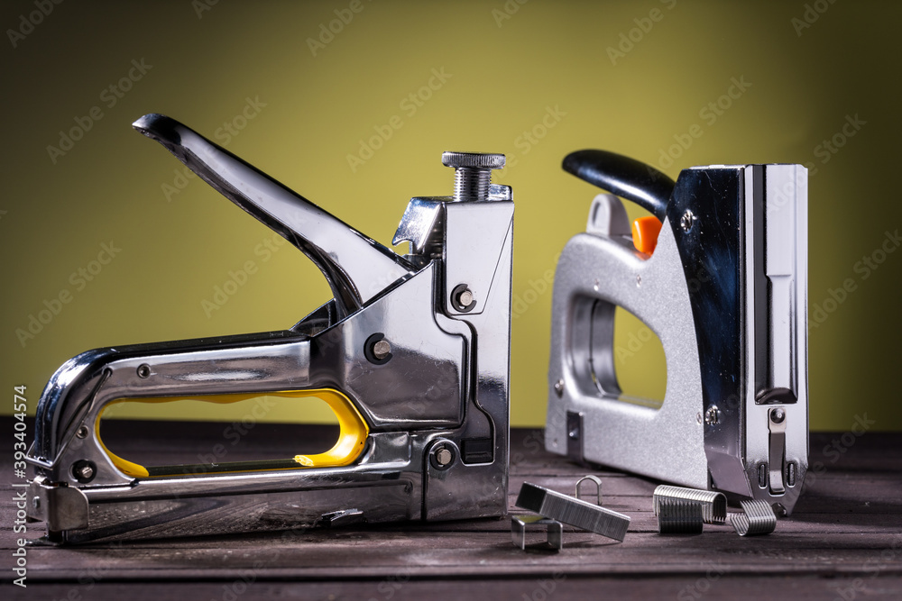 Two silver construction staples on a wooden table with staples, on a yellow background Two silver construction staples on a wooden table with staples, on a yellow background