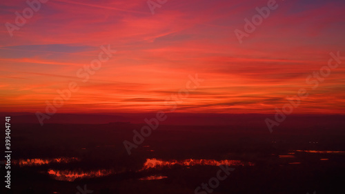Red-orange sky after sunset. Red clouds are reflected in the lakes. Aerial photography, moody shot. Photos perfect for background exchange.