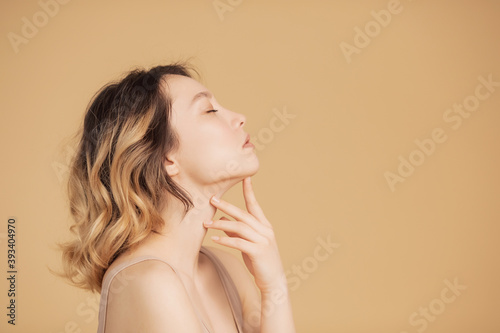 Profile young girl of Asian appearance with wavy streaked hair on beige background. Concept beauty and fashion of face and body skin