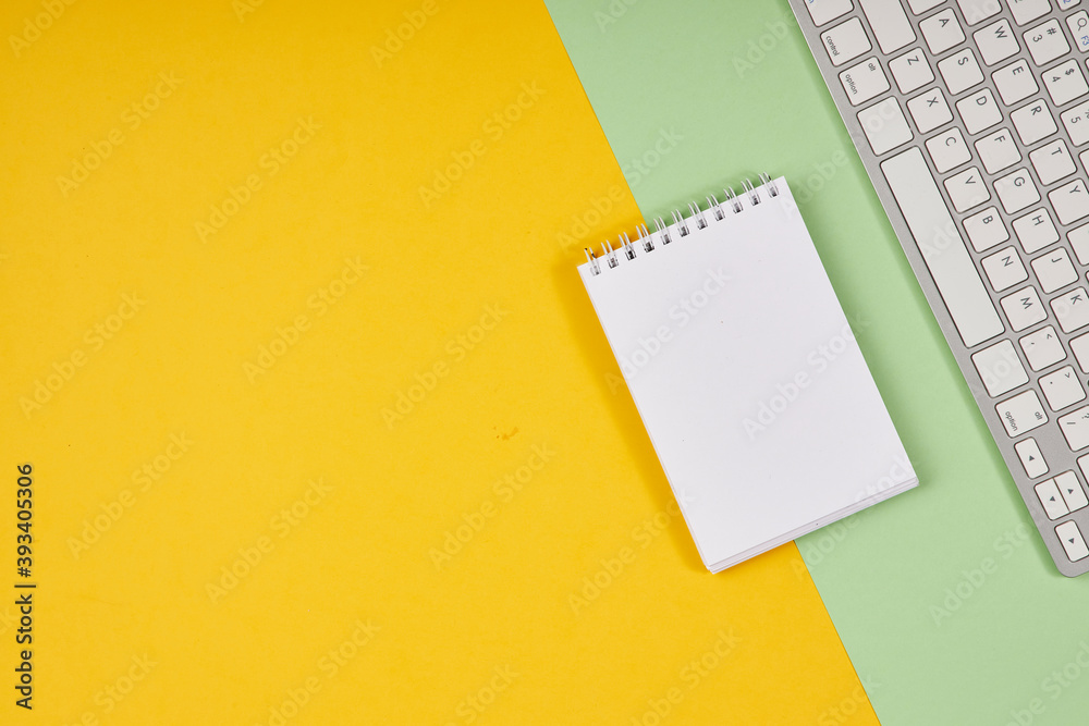 Yellow and green office desktop. Top view table with notepad, keyboard. Mock up, copy space. Yellow and green office desktop. Top view table with notepad, keyboard. Mock up, copy space.