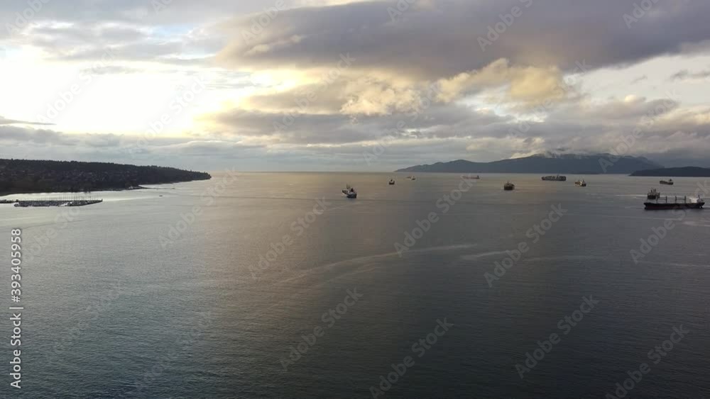Fly over bay in Vancouver on a beautiful sunny evening with cargo ships waiting