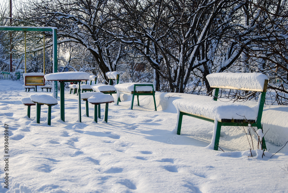 Snow-covered playground with swings and benches