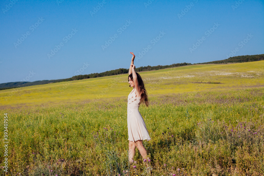 Portrait of a beautiful fashionable woman in a dress in a field with yellow flowers Portrait of a beautiful fashionable woman in a dress in a field with yellow flowers