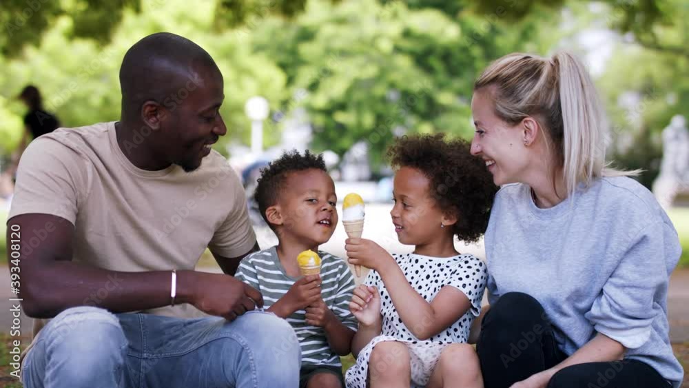 Multiracial family on walk in public park eating ice cream.