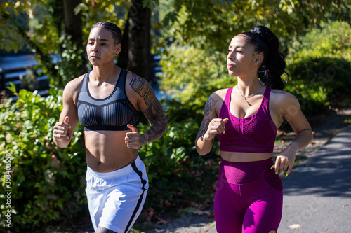 Two woman working out together running outside on a trail