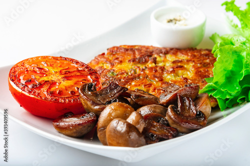 Potato pancakes with lettuce leaves, fried mushrooms, grill vegetables and blue cheese sauce. White background. Close up. Selective focus.