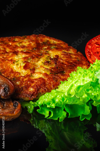 Potato pancakes with lettuce leaves, fried mushrooms, grill vegetables and blue cheese sauce. Black background.  Close up. Selective focus.
