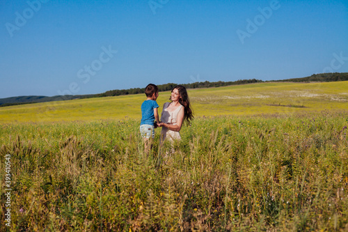 Beautiful woman mom hugs young son in nature on a walk